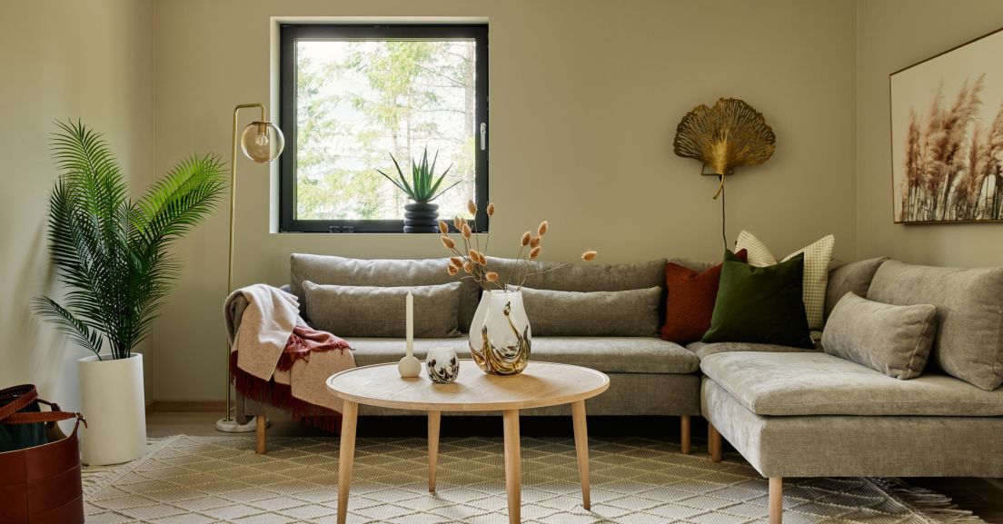 Bilde av en møblert stue med sofa, stuebord og beigemalte vegger