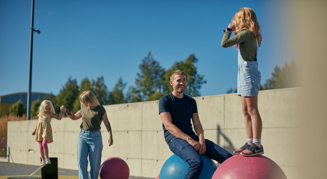 Foto av en familie som leker på en lekeplass på Kløfta.