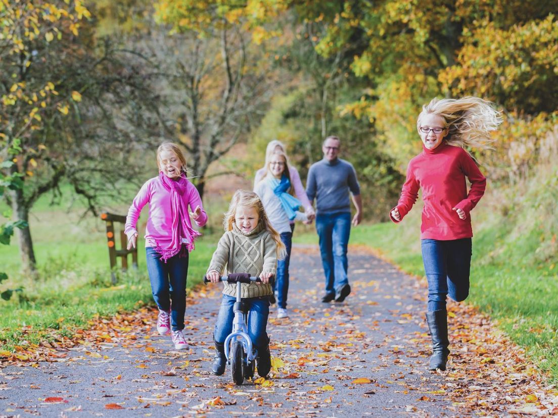 Familj ute på promenad en vacker höstdag