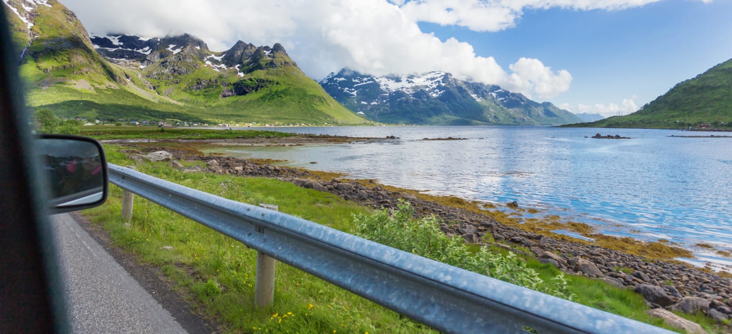 Fjord og fjellandskap, tatt fra innsiden av en bil