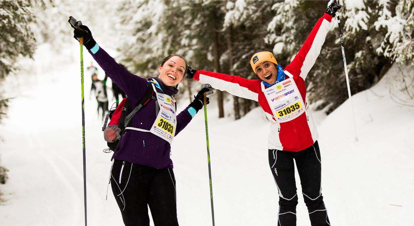 To kvinner på skitur i snøkldd skog jubler.