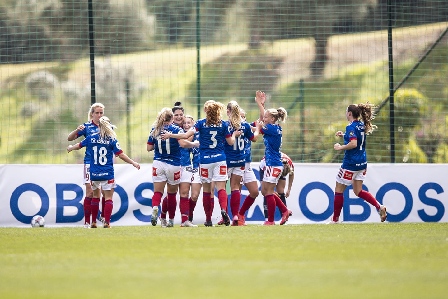 En gjeng kvinnelige fotballspillere som løper mot hverandre i glede på fotballbanen