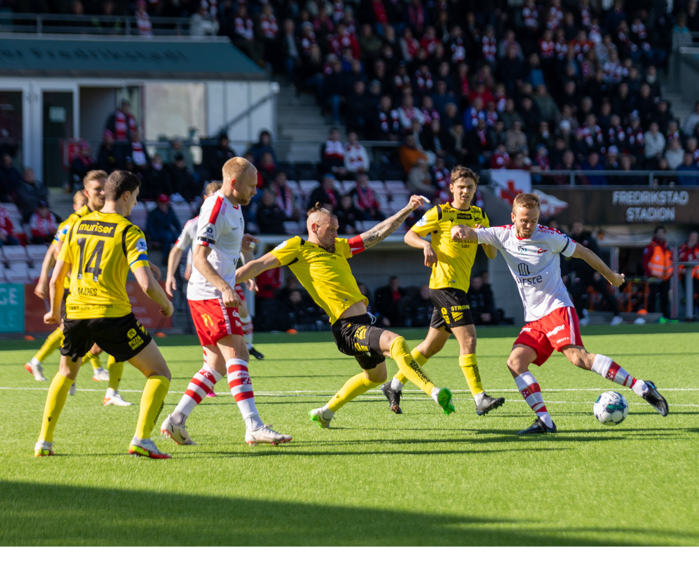 En gruppe mannlige fotballspillere under en fotballkamp som duellerer for å få tak i fotballen