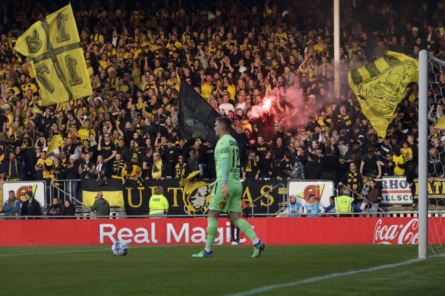 Foto av LSK sin keeper i grønn drakt med LSK supportere som heier fra tribunen i bakgrunnen