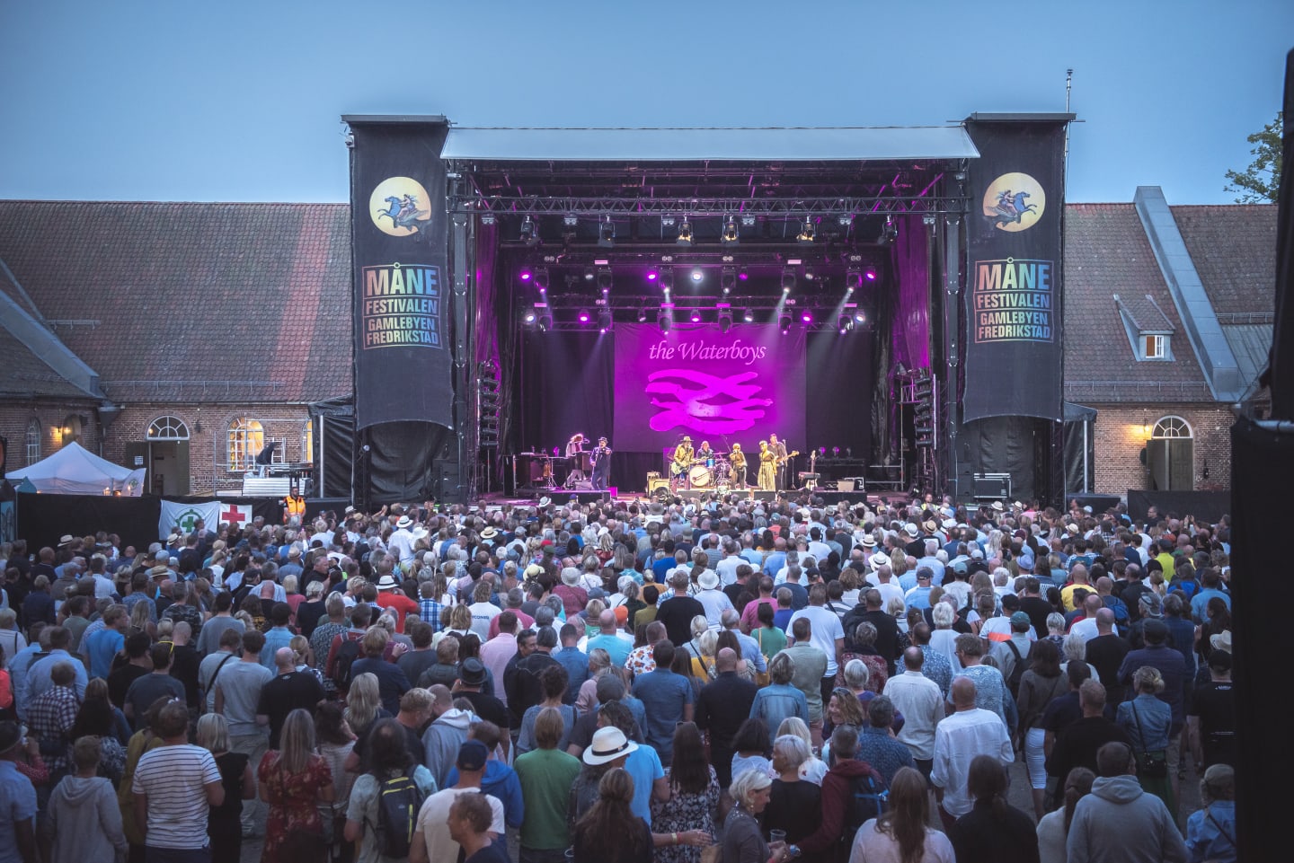 Foto av Månefestivalen med en lilla lys på scenen og publikum som står og hører på konserten.