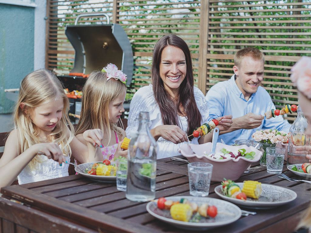 En familj äter middag utomhus i solskenet
