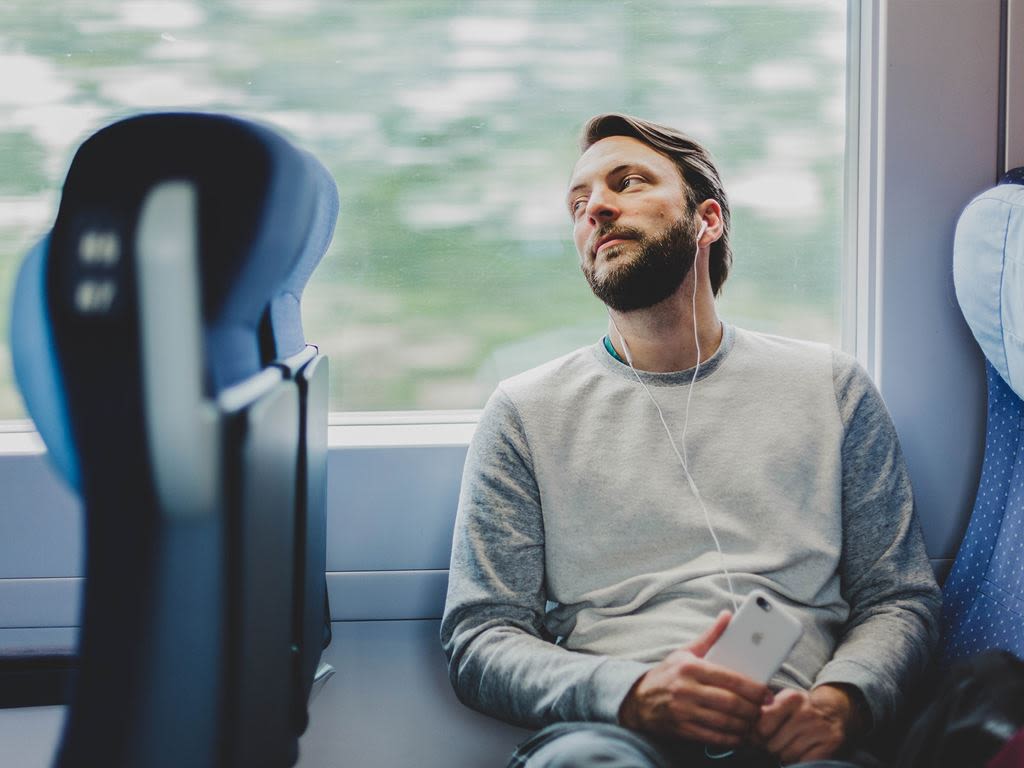 En kille sitter på en buss och lyssnar på musik