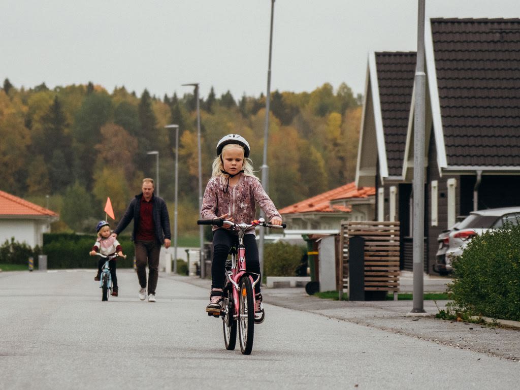 familj är ute och cyklar på kvarterets gata