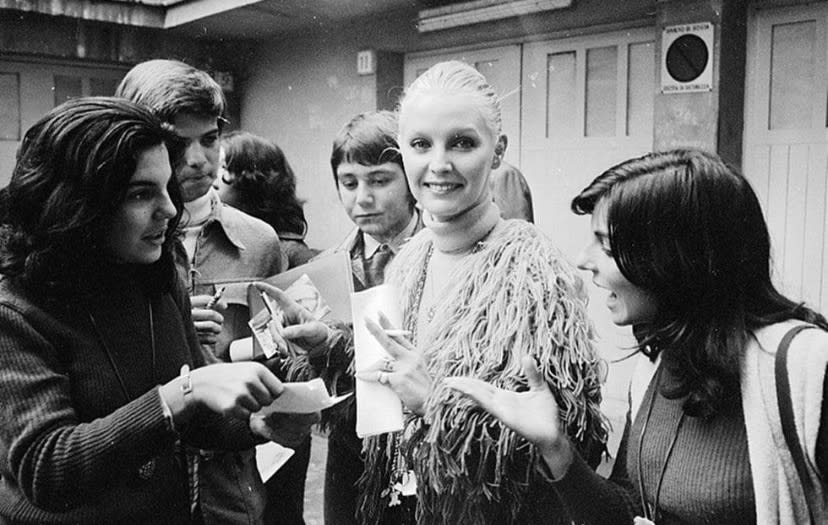 Patty Pravo sorride tra le persone mentre firma autografi