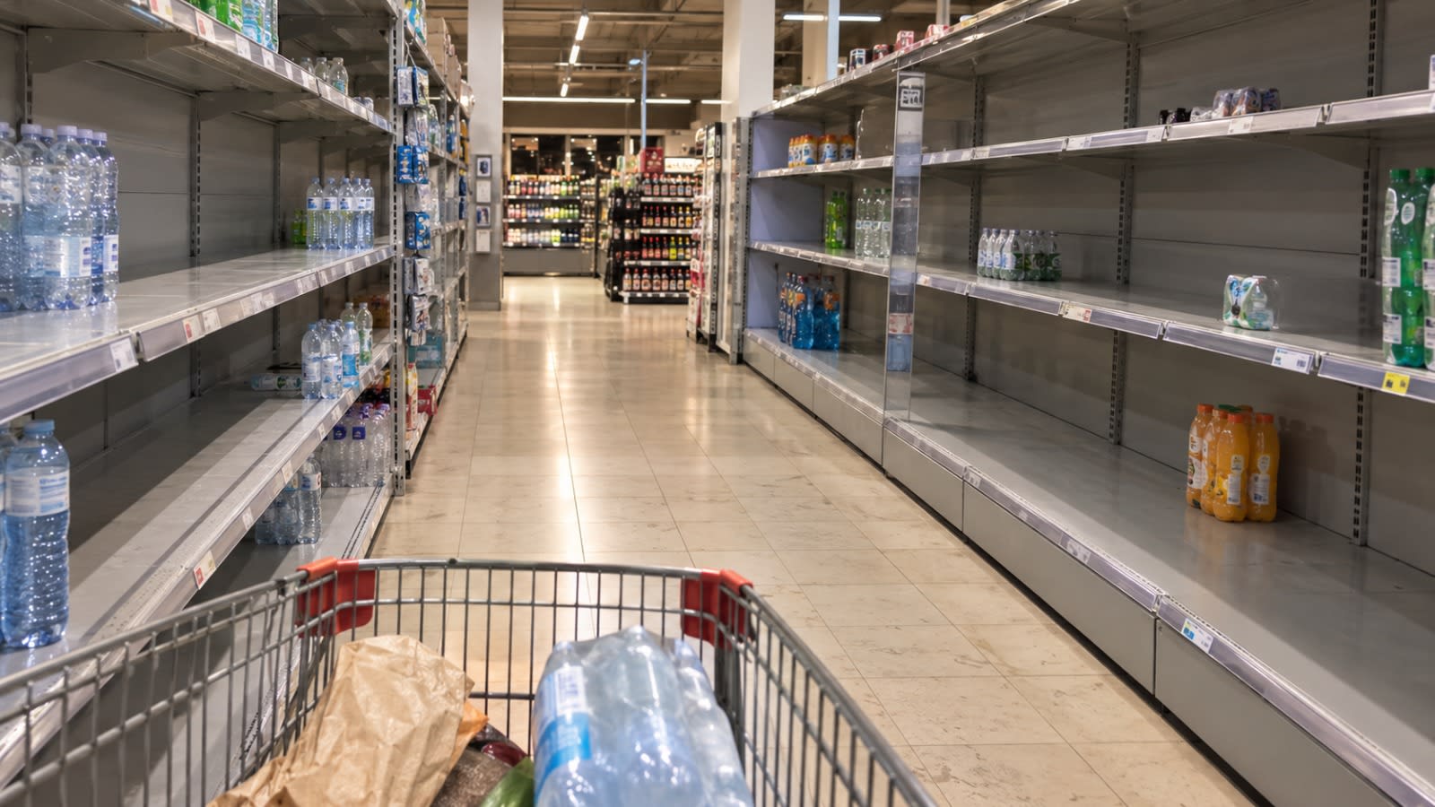 Corsia di un supermercato con scaffali in gran parte vuoti