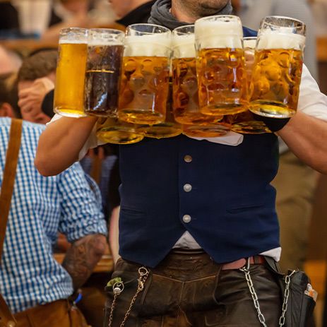 Man carrying multiple steins at Octoberfest