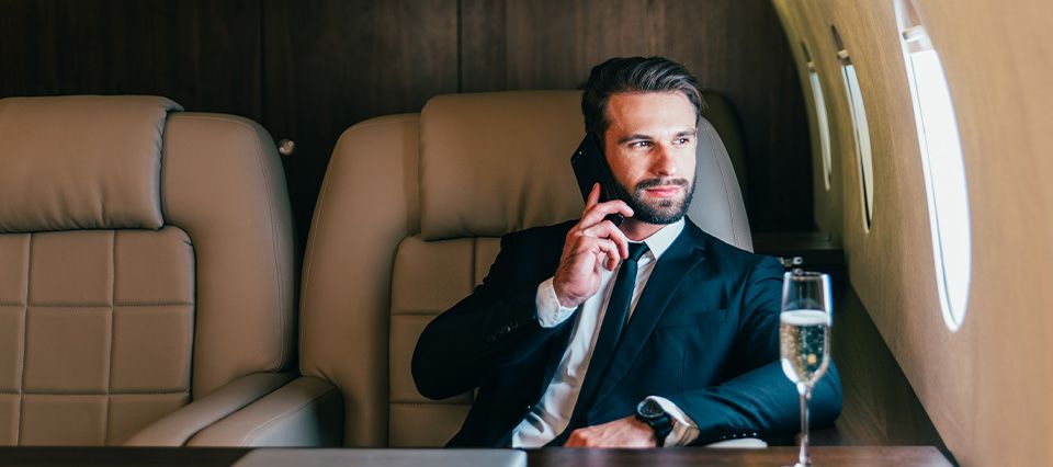 Man on the phone in business attire travelling on private jet