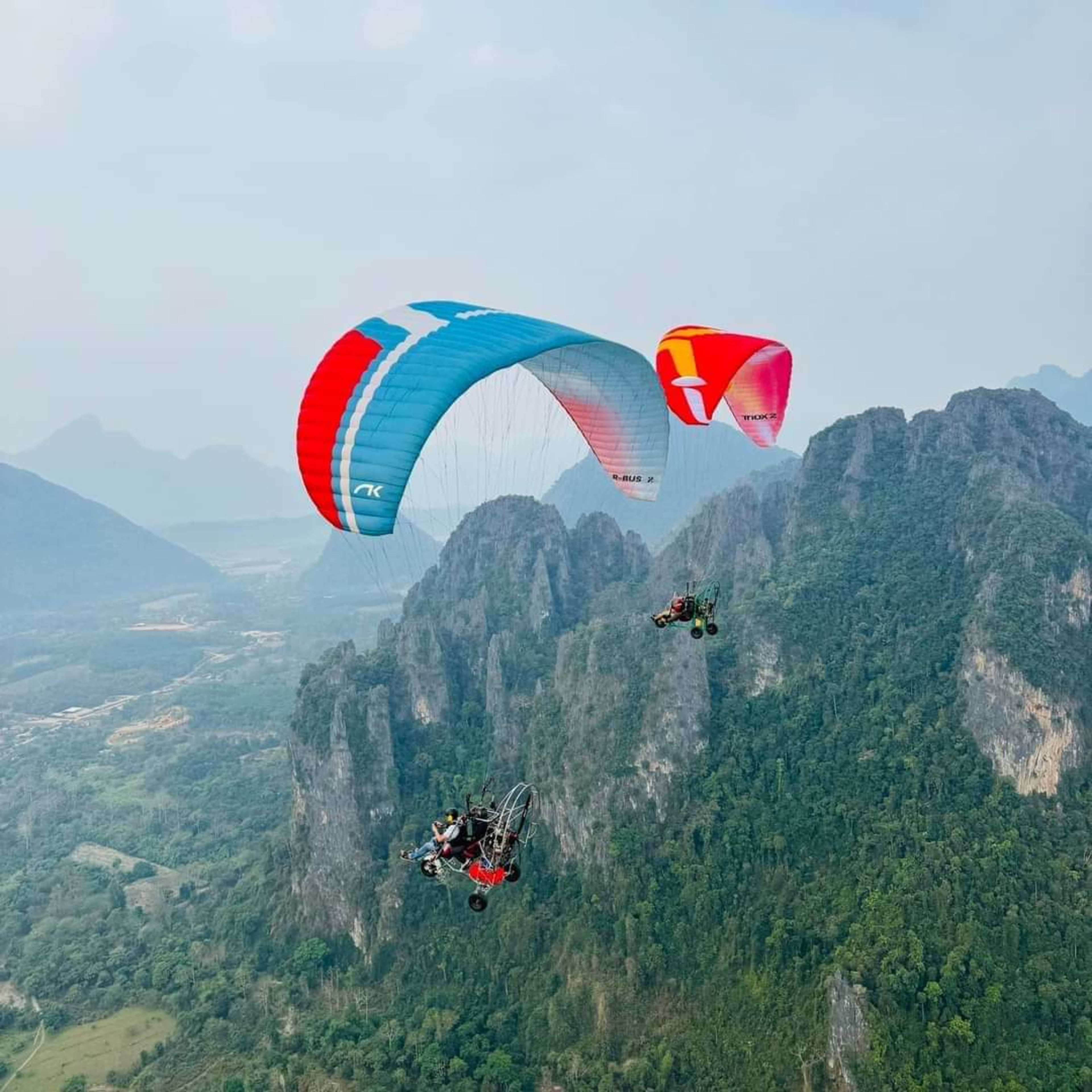 Tandem paramotors soaring over the karst peaks of Vang Vieng