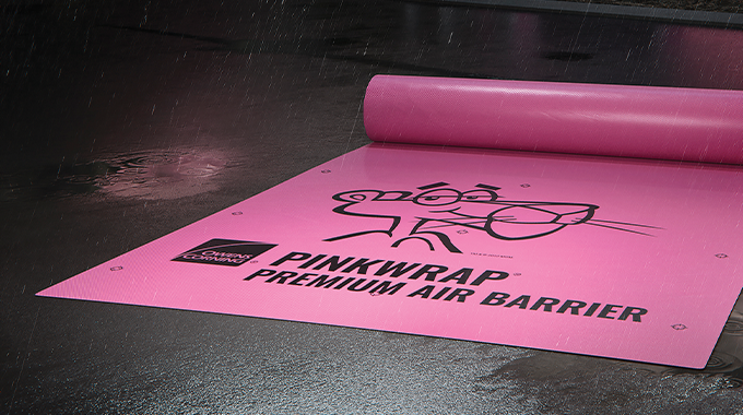 Owens Corning Roofing PinkWrap Premium Air Barrier unrolled on dark, wet pavement