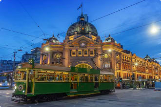 Tram passing Flinders Street Station at dusk
