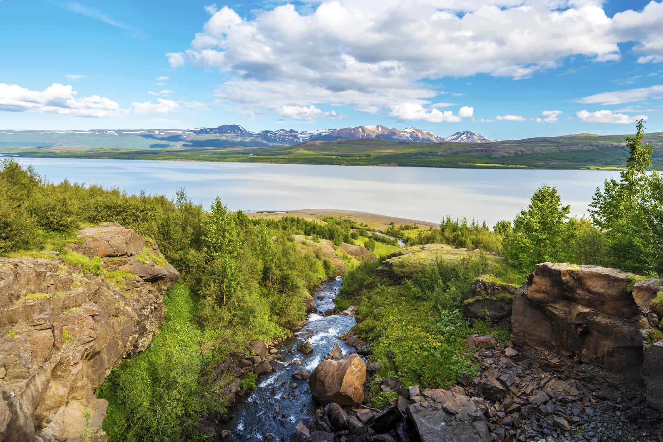 Water course falling down to Lagarfljot lake in Eastern Iceland, the mountain landscape of Fljotsdalsherad municipality is at background