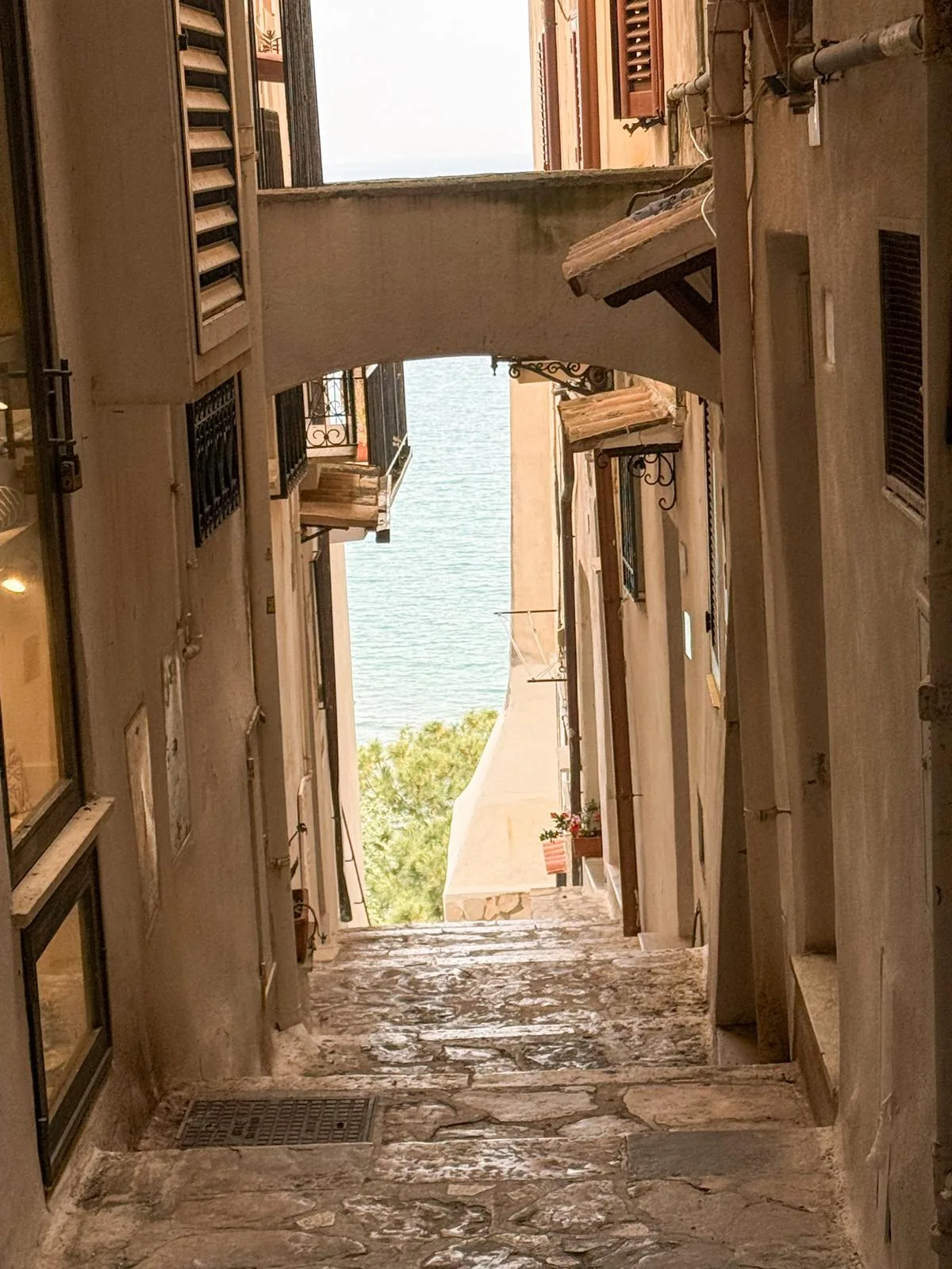 A narrow alley between shuttered buildings opening onto the sea