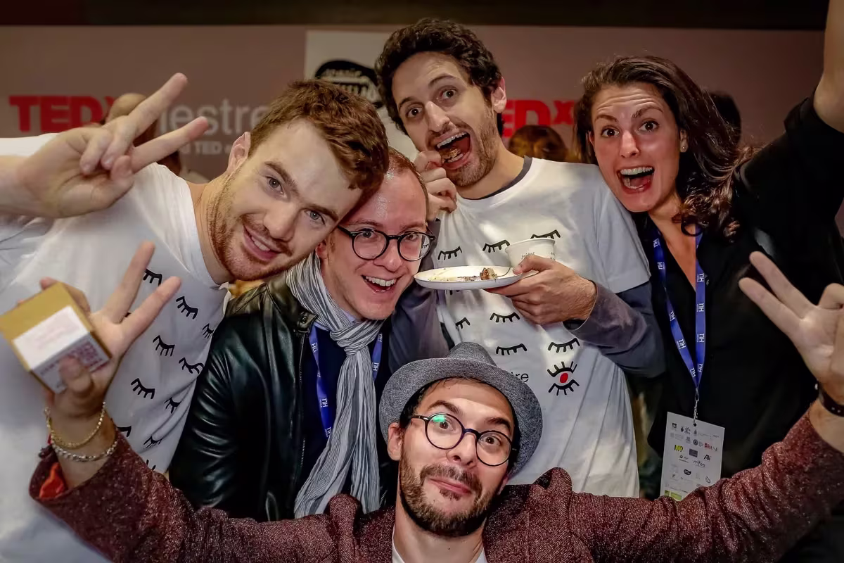 Partecipanti del TEDx Mestre stretti davanti alla fotocamera, con il fondale dell’evento alle spalle