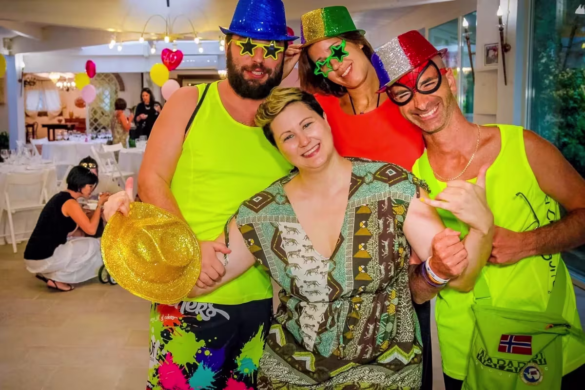Amici con cappelli colorati, occhiali e canotte fluo a una festa di compleanno a Padova