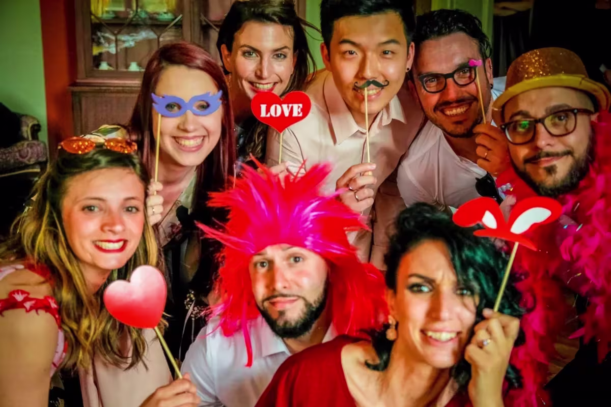 Invitati stretti davanti all’obiettivo con parrucche rosa, cuori e baffi finti al Castello Papadopoli di Treviso