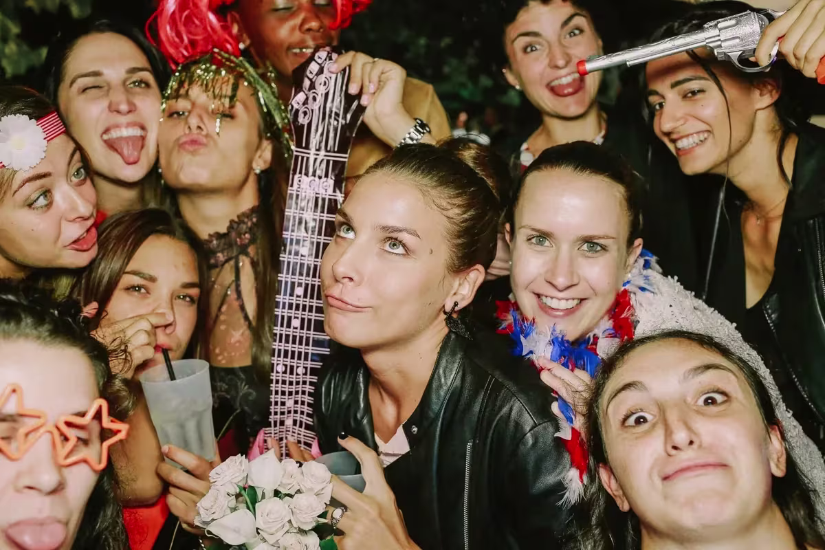 Amiche che si stringono verso l’obiettivo con occhiali a stella e una chitarra gonfiabile