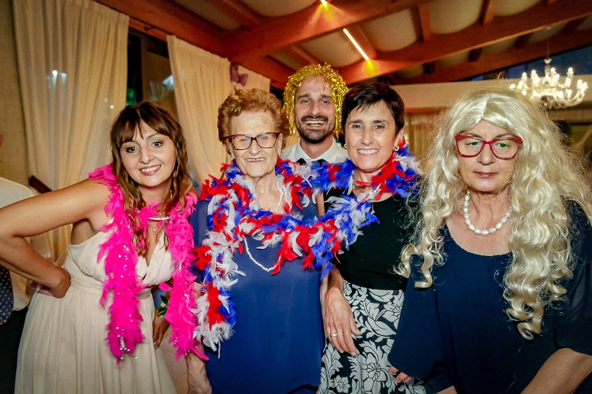 Five guests posing in front of the booth with colourful feather boas around their necks