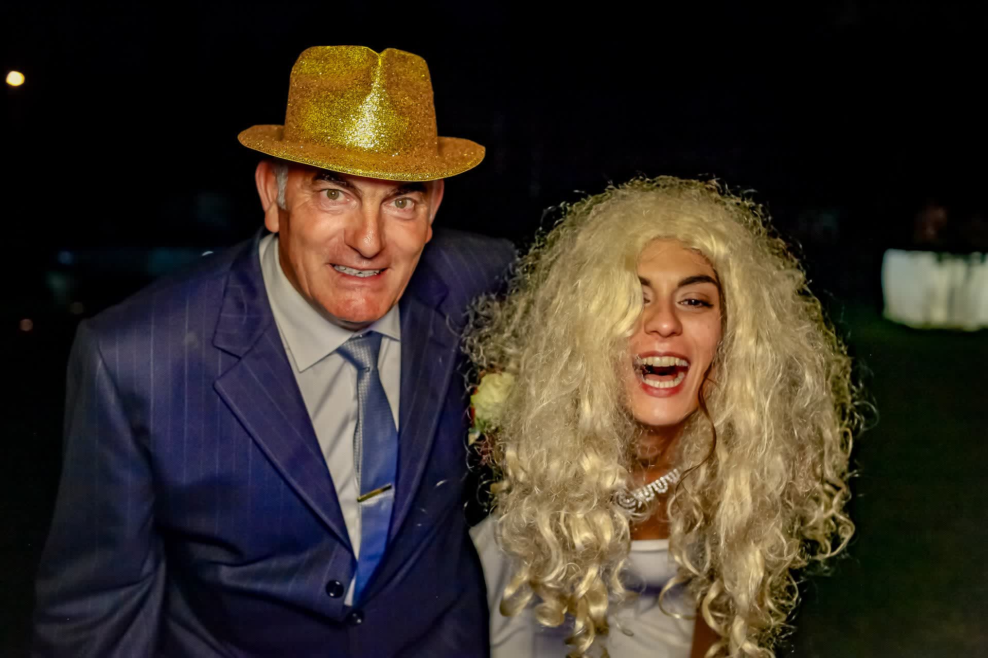 Due invitati di sera, uno con cappello dorato e l’altra con una lunga parrucca bionda
