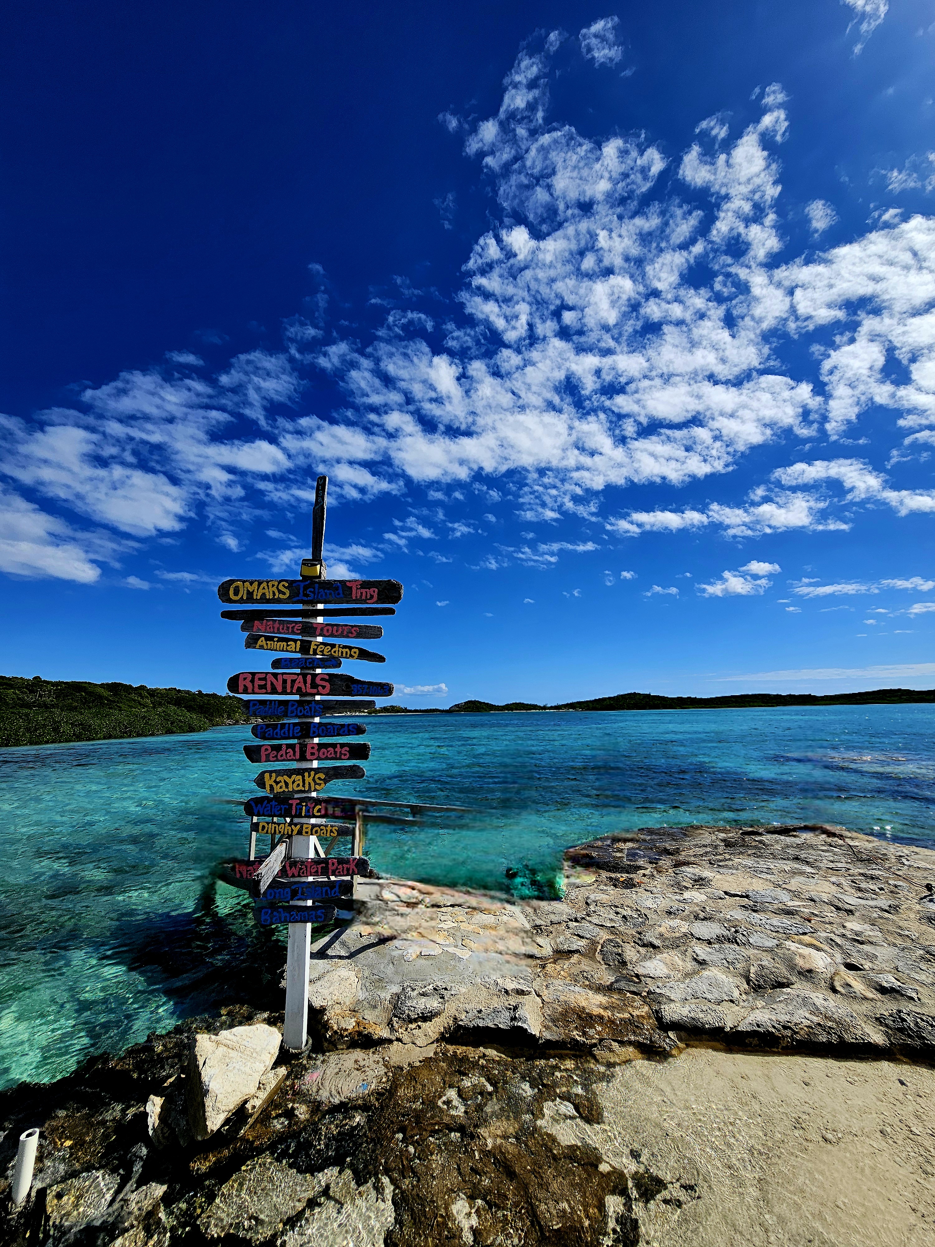 Colorful destination signpost over turquoise Caribbean water