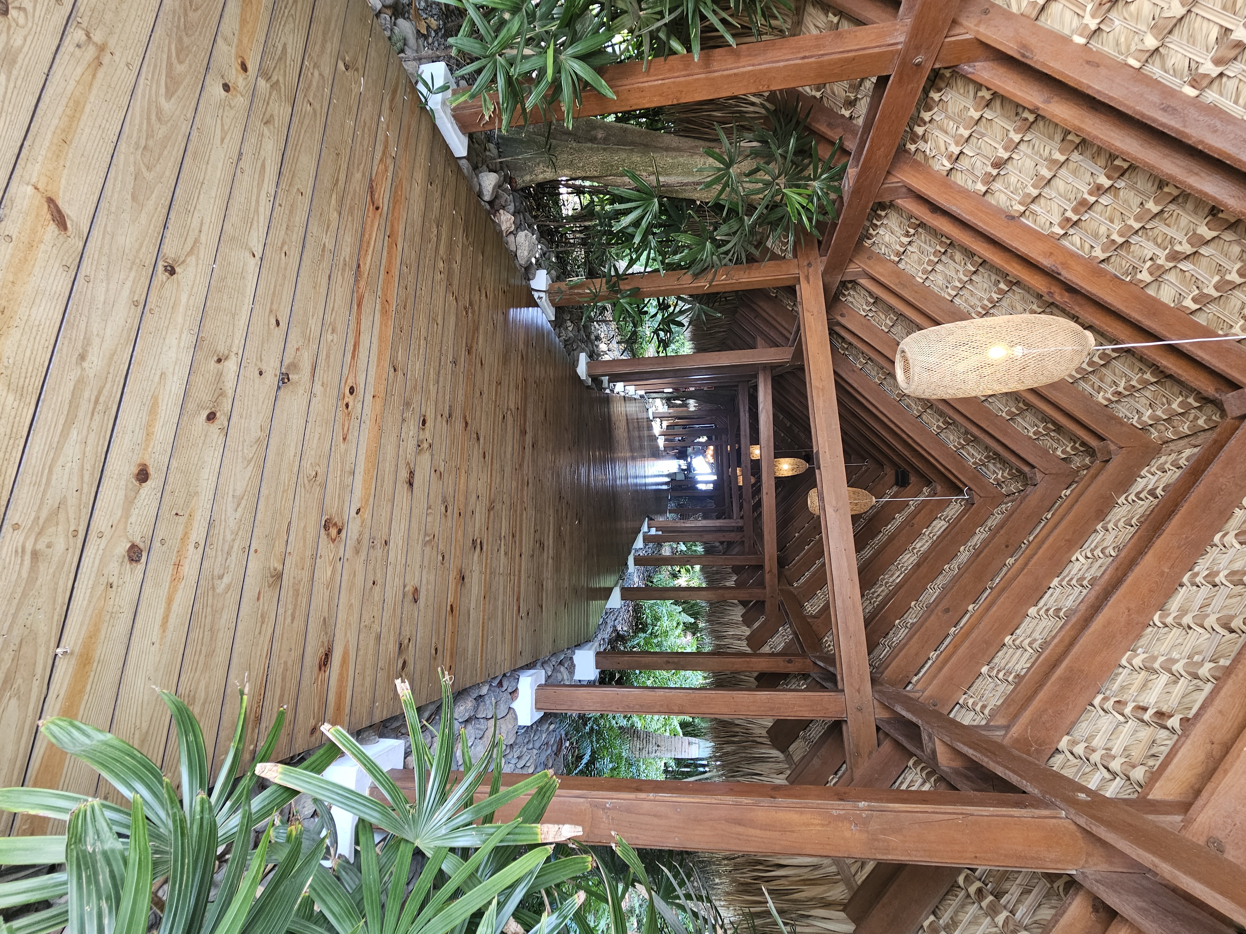 Tropical resort walkway with thatched palm roof and rattan lanterns