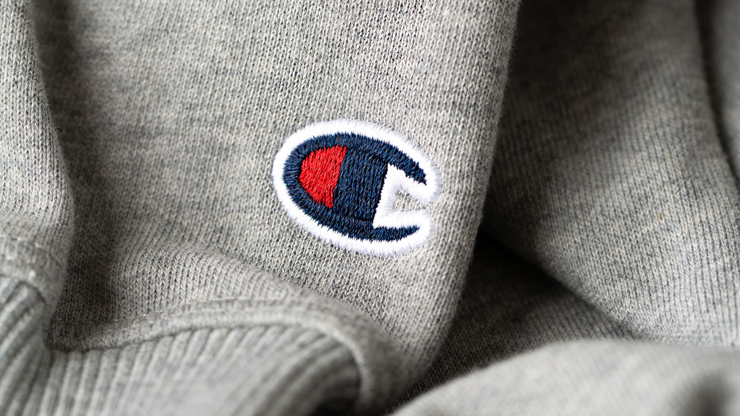 Detail shot of embroidered Champion logo on a hoodie sleeve