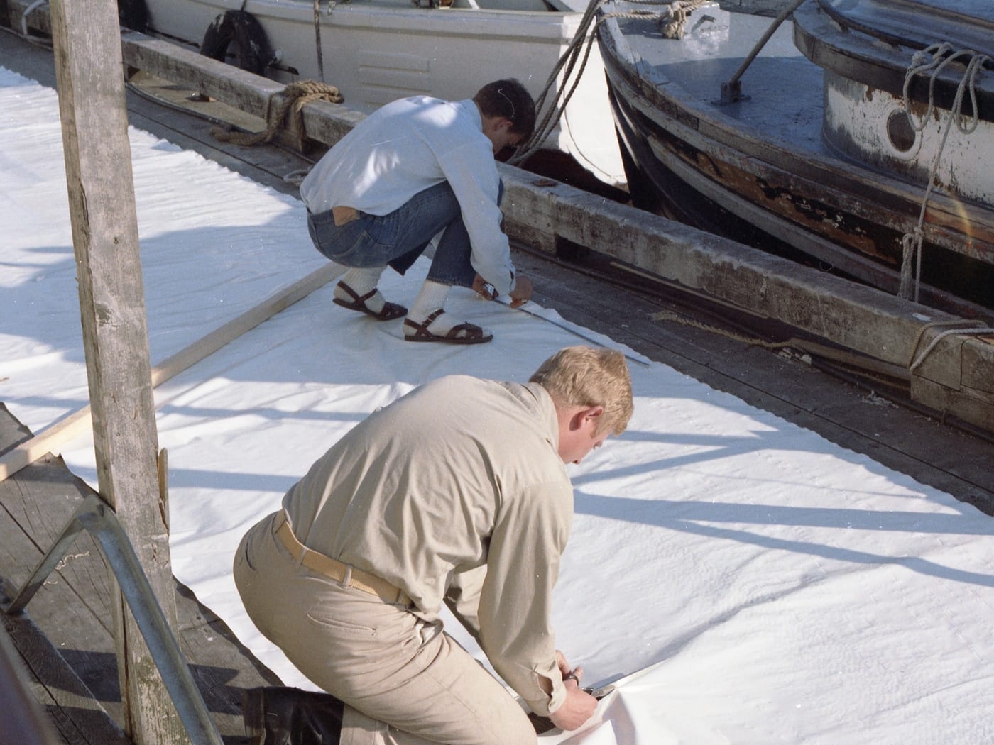 An image of a man in beige pants and dress shirt cutting signal cloth for draping a hydrographic signal with by @noaa on unsplash.