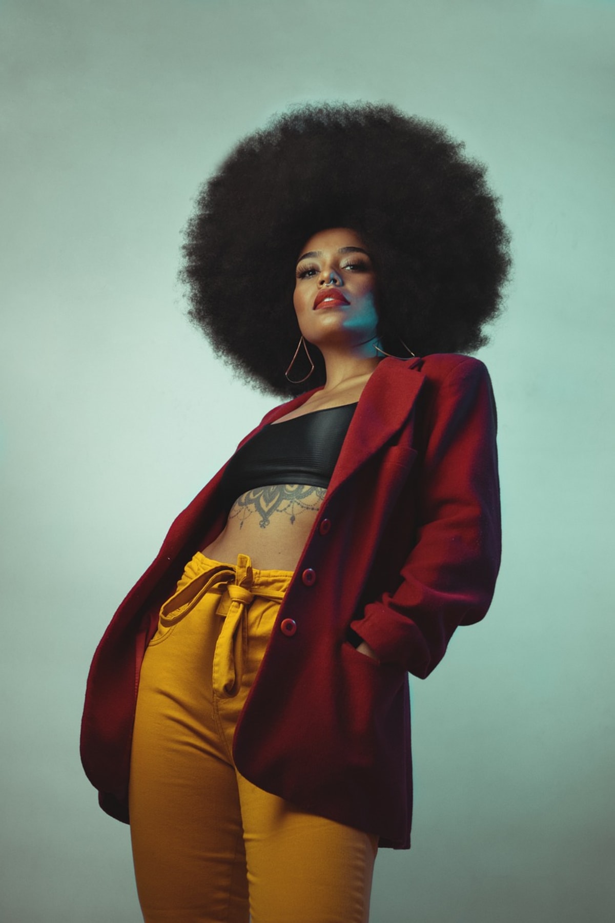 Confident woman with natural hair in warm burgundy and gold tones, embodying the phenomenal strength and self-assurance celebrated in Maya Angelou's poem