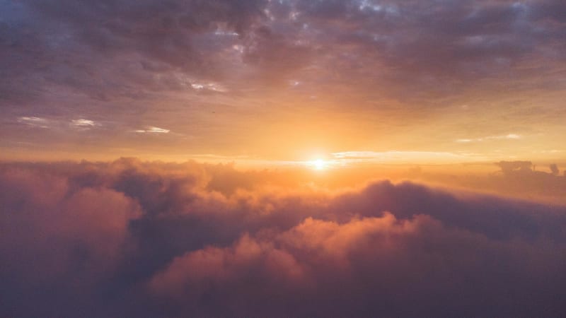 Expansive golden sky with dramatic clouds illuminated by warm sunlight, representing the transcendent and limitless nature of feminine empowerment