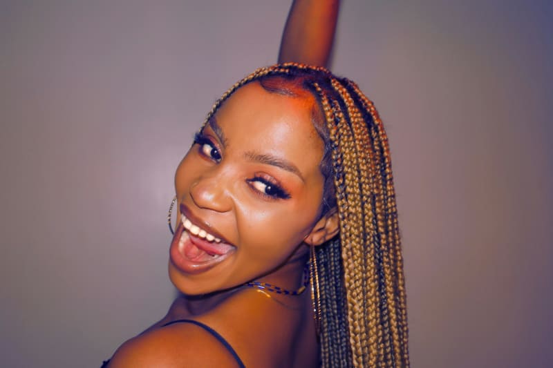 Joyful woman with beautiful braids laughing with pure happiness, embodying the flash of teeth and joy in feet described in Maya Angelou's poem