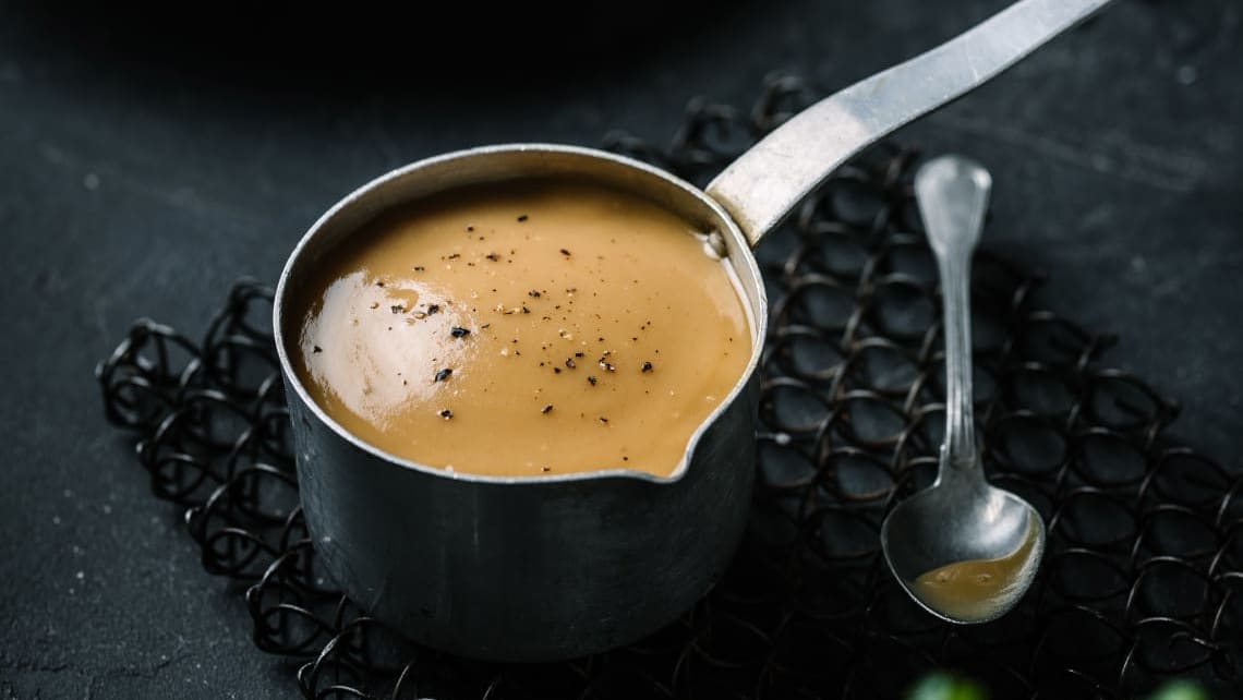 En liten kjele med Sennep- og honningsaus, toppet med krydder som pynt