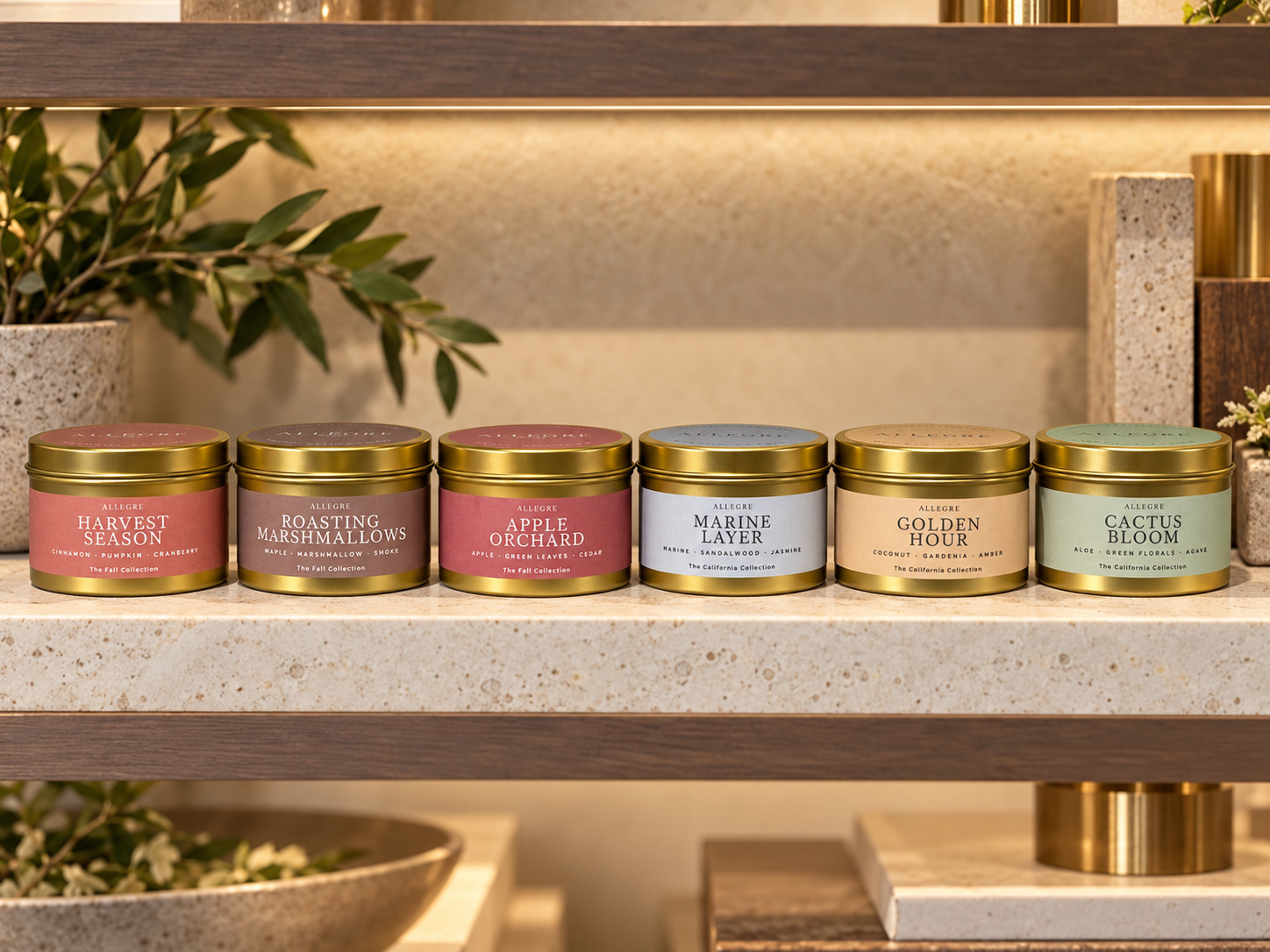 ALLEGRE luxury coconut-soy candles displayed in gold tins on a boutique retail shelf, featuring Fall Collection scents Harvest Season, Roasting Marshmallows, and Apple Orchard, alongside the California Collection.