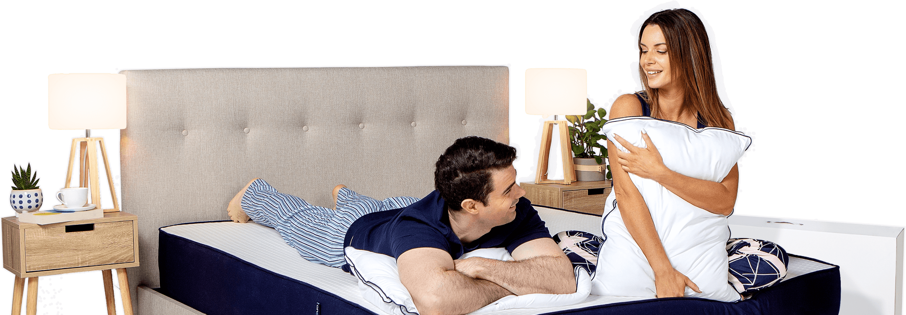 Couple talking in bed - the man laying on it stomach and the girl on her knees