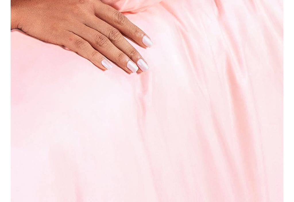 Person's heand on top of Onebed Creamy Peach Sheets