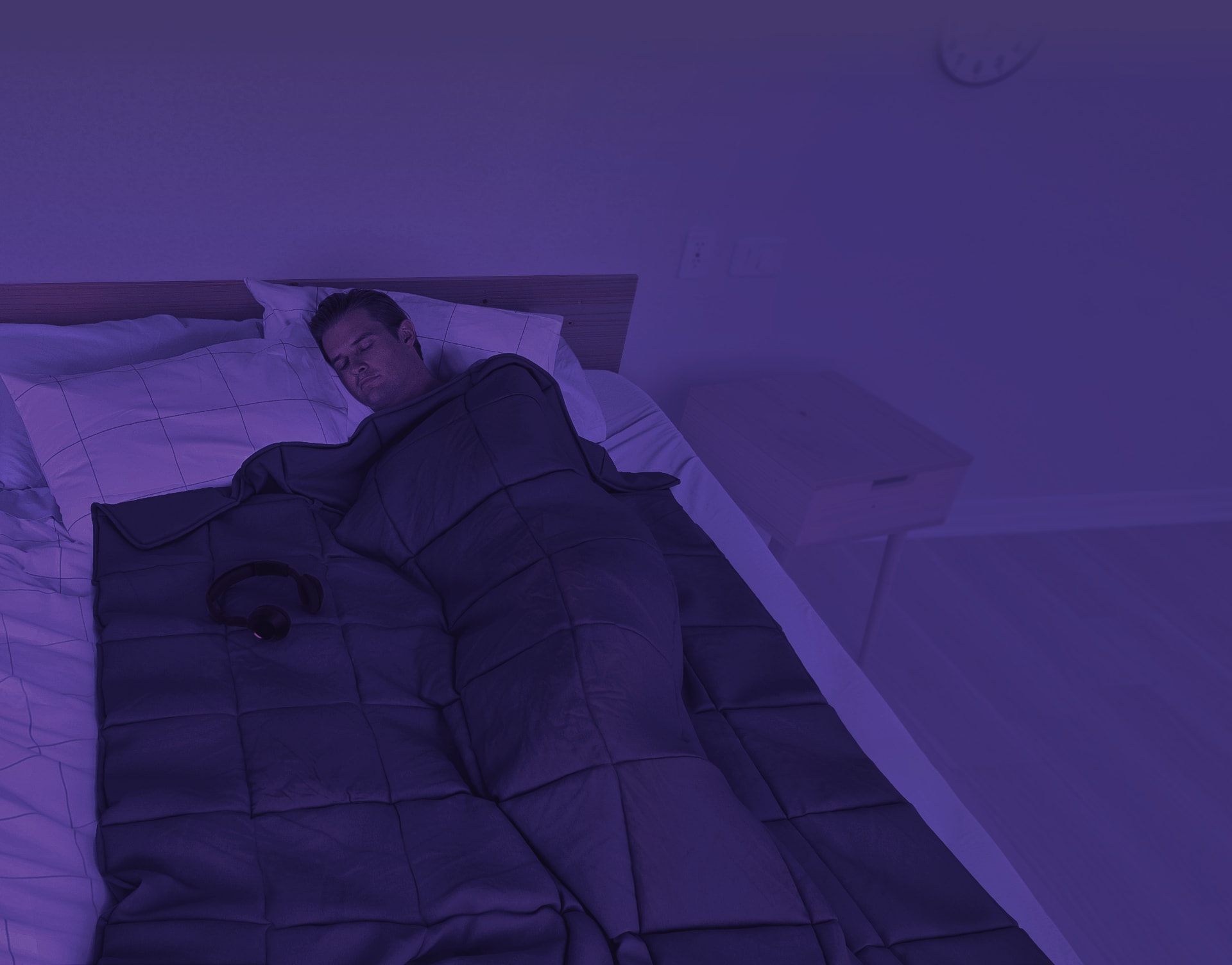 Person in dark room sleeping with the Onebed Weighted Blanket on top.