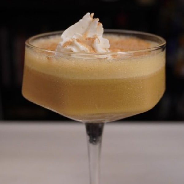 RumChata pumpkin pie martini in a coupe glass topped with whipped cream and a dusting of pumpkin spice