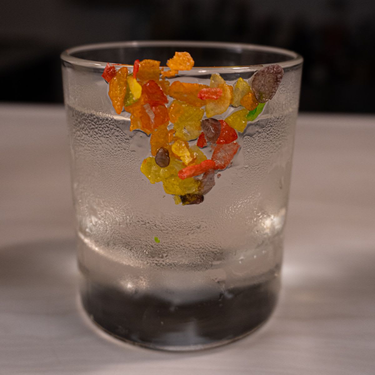 Cereal Negroni in a rocks glass with Fruity Pebbles stuck to the inside of the glass, made with Junction 35 Bam Bam vodka, Luxardo Bitter Bianco, and dry vermouth