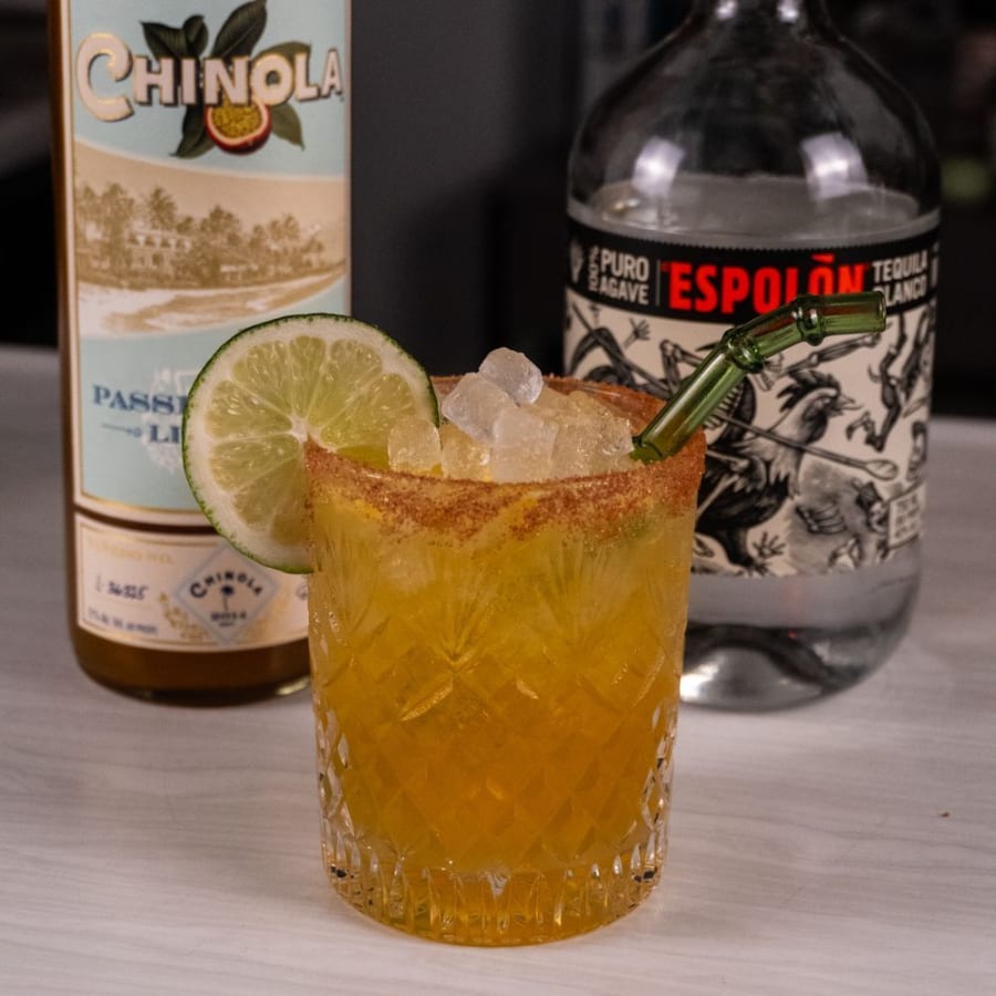 Passion fruit margarita made with Chinola liqueur, with a tajin rim and lime wheel