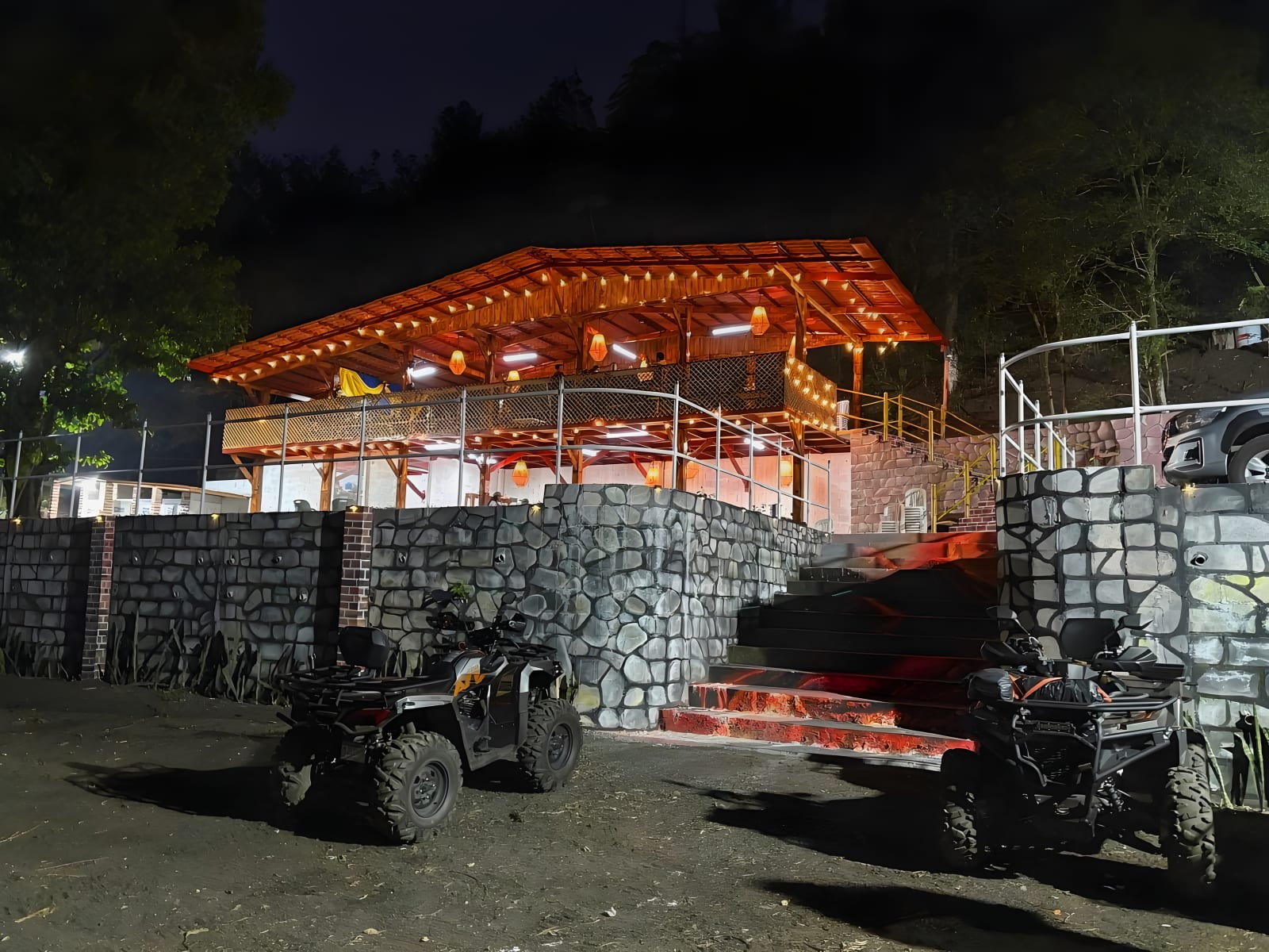 The restaurant lit up at night with ATVs in front