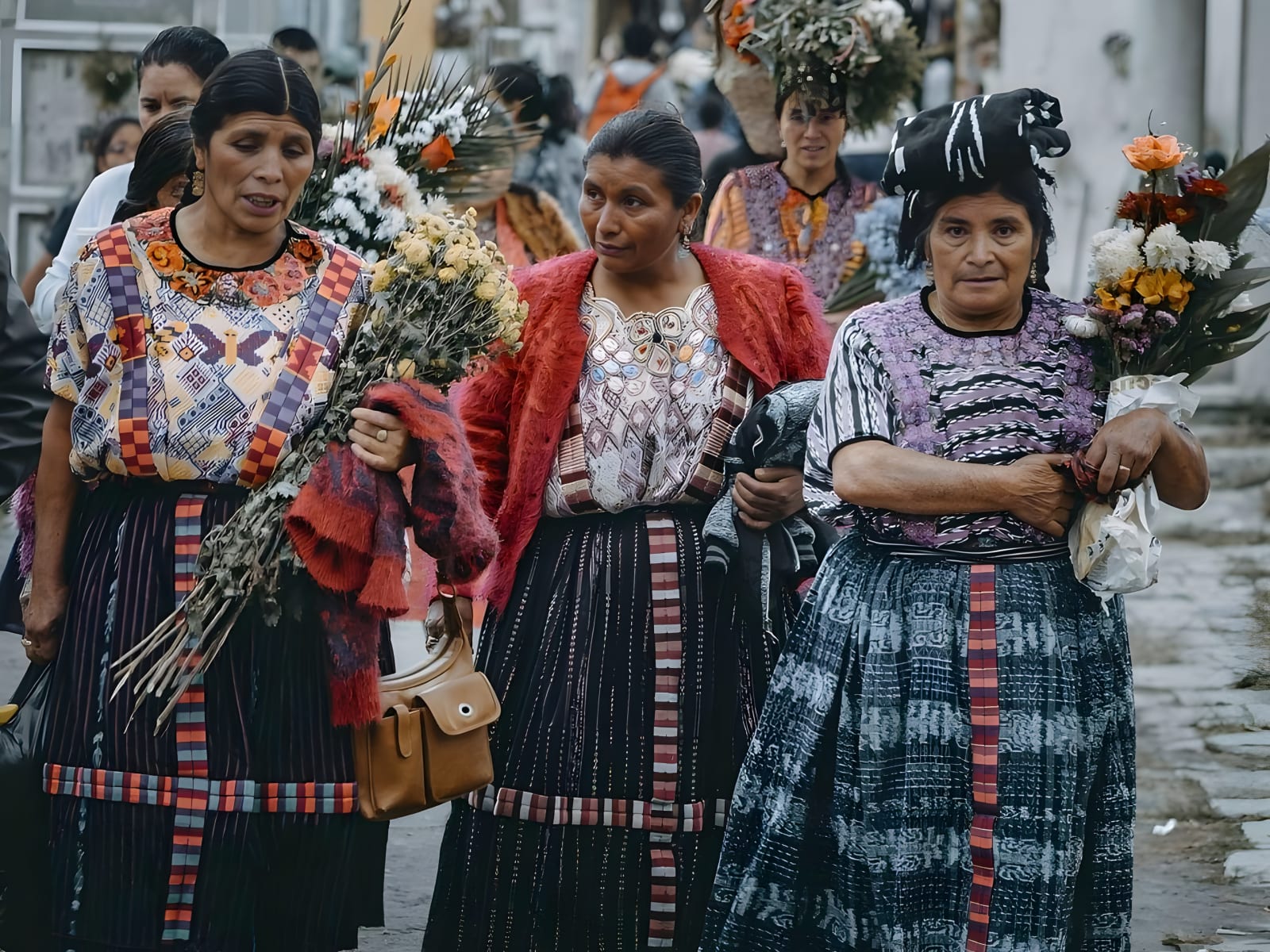 Women in traditional Guatemalan dress carrying flowers
