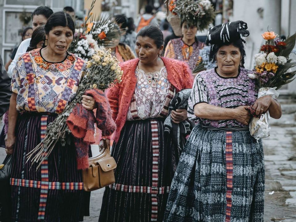 Mujeres con traje típico guatemalteco llevando flores