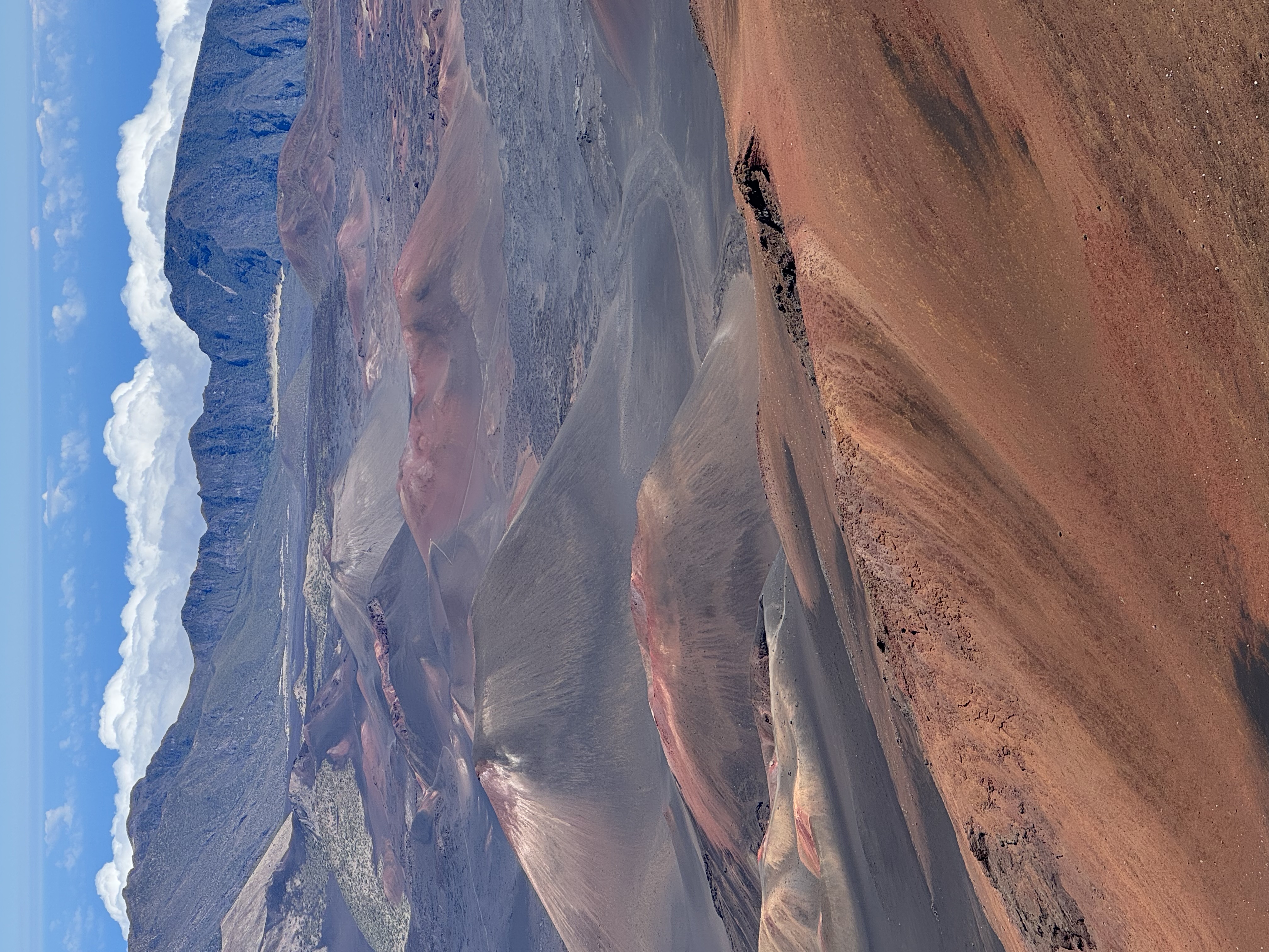 Haleakalā crater cinder cones — vibrant red and orange volcanic formations rising above the clouds