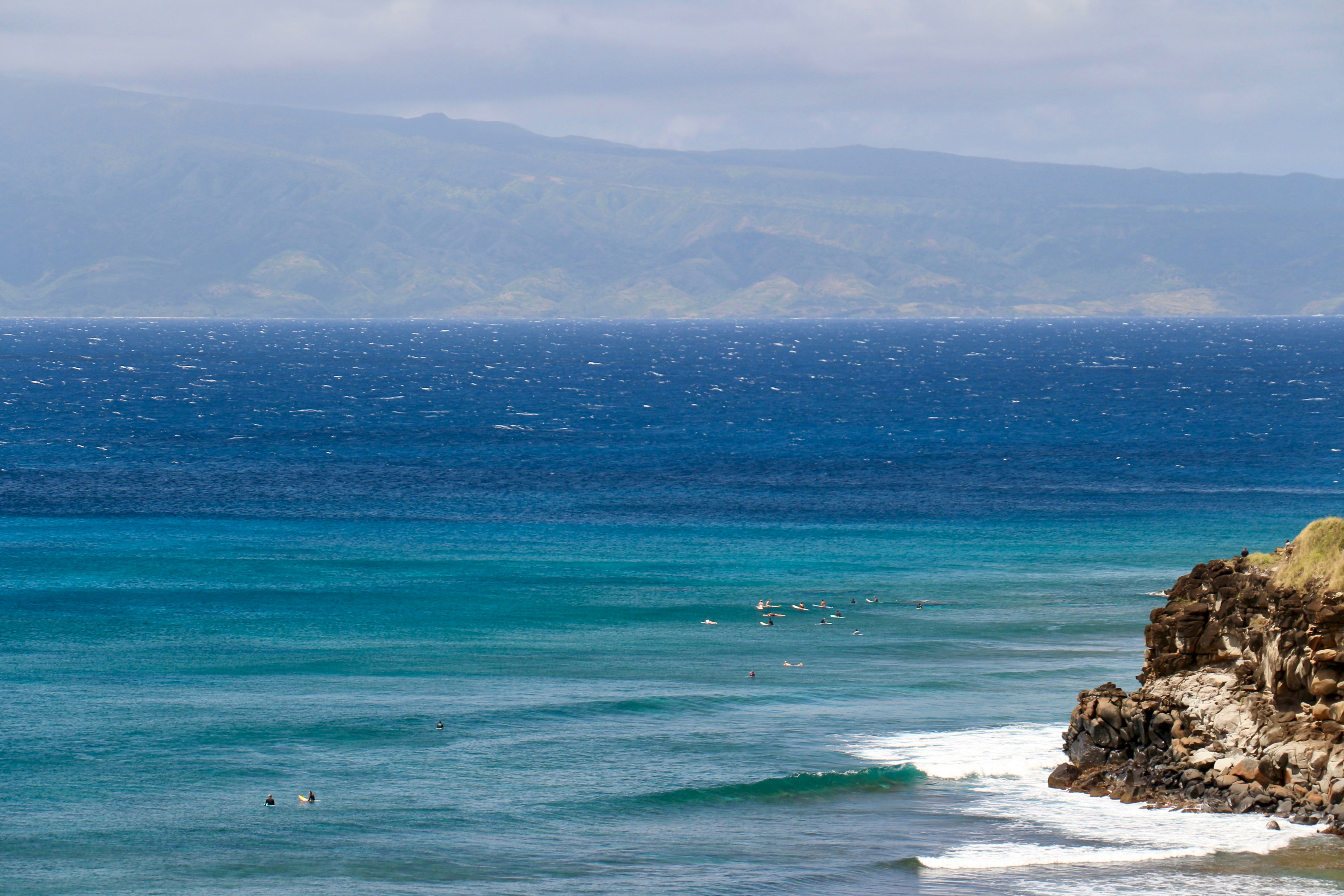 Surfers at Honolua Bay, Maui — the bay's rocky point break draws big wave riders during the winter swell season