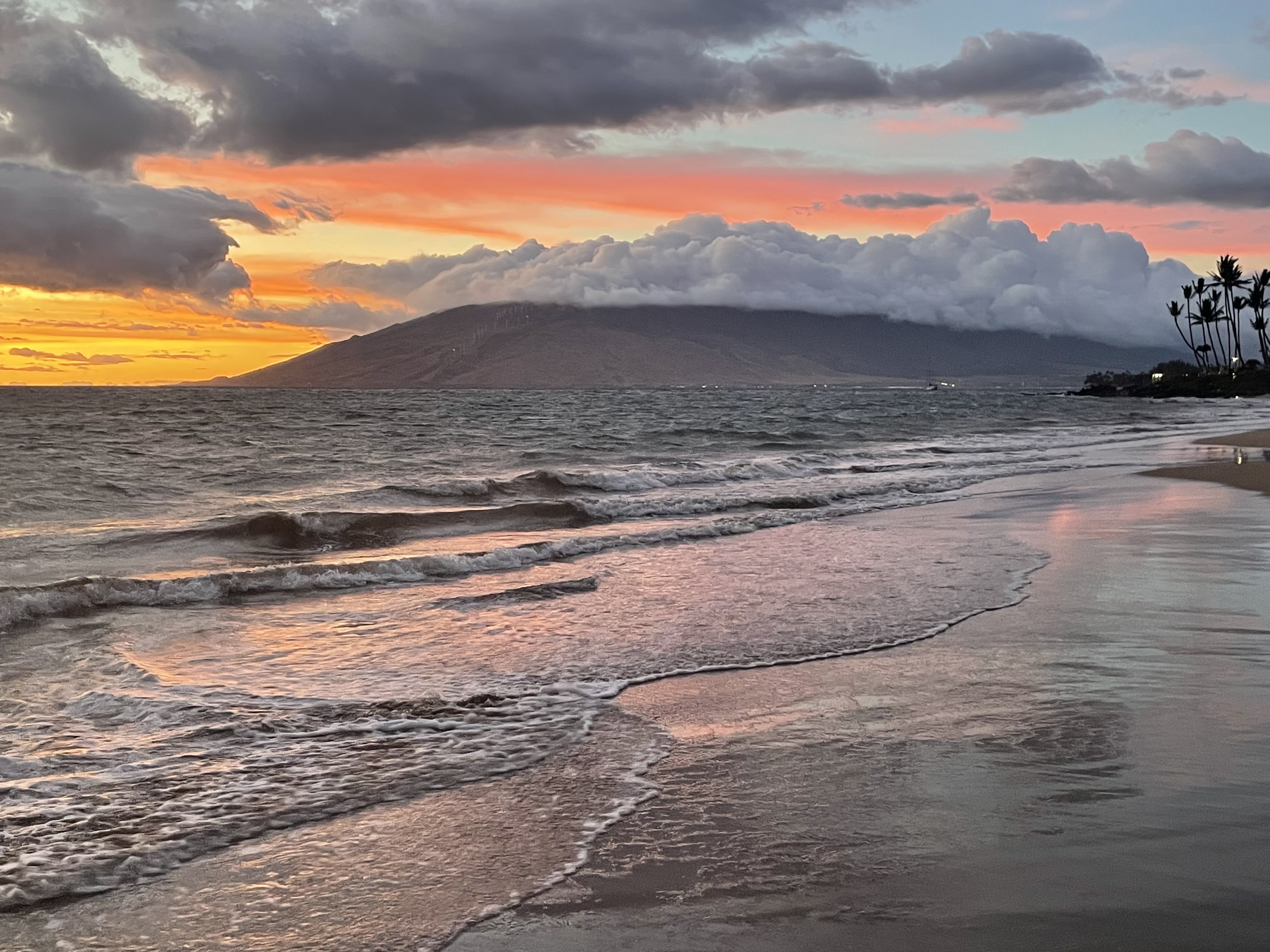 Kama'ole beach at sunset with West Maui mountains reflected in calm water — October 2021
