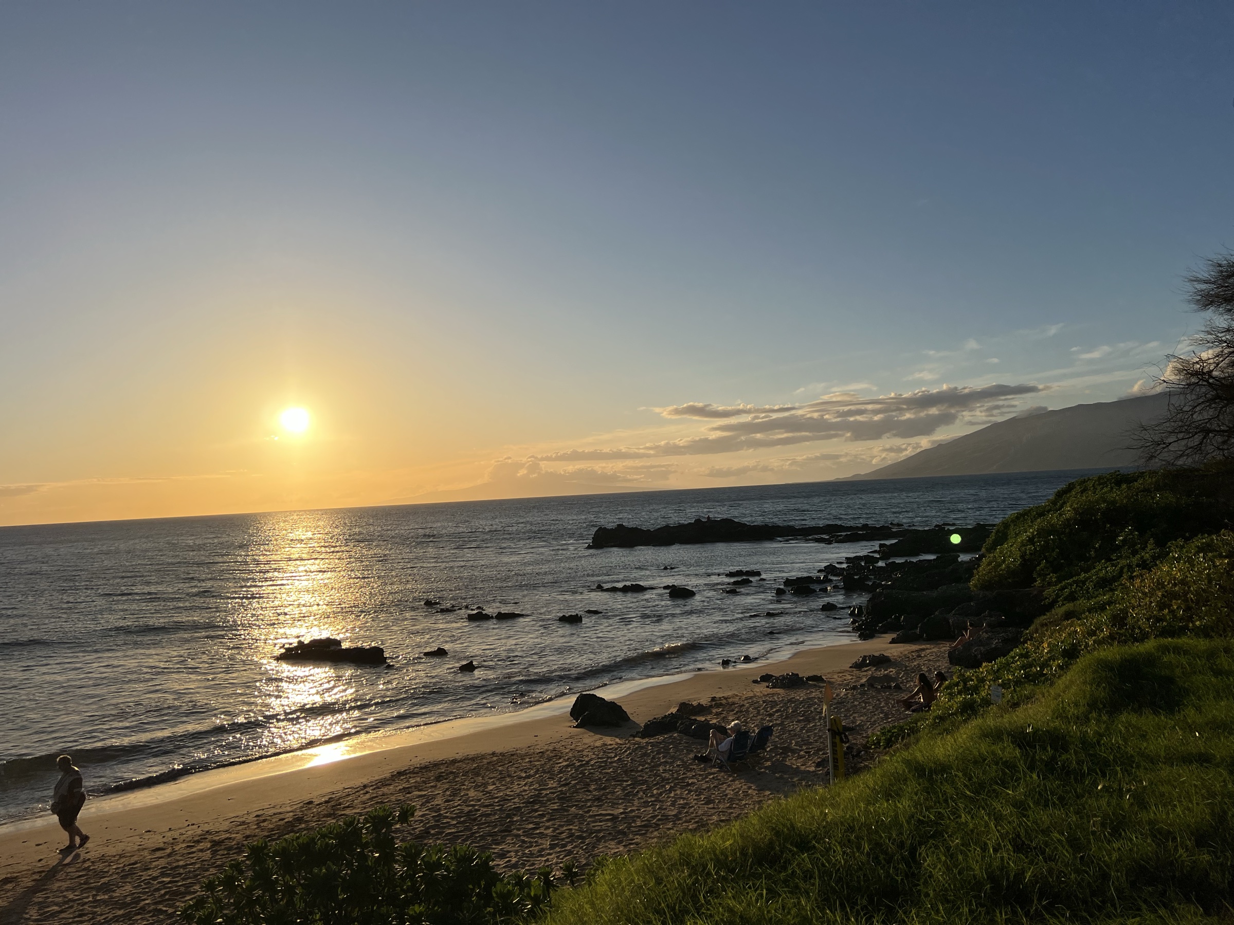 Sandy Kama'ole cove at sunset with people relaxing on the beach