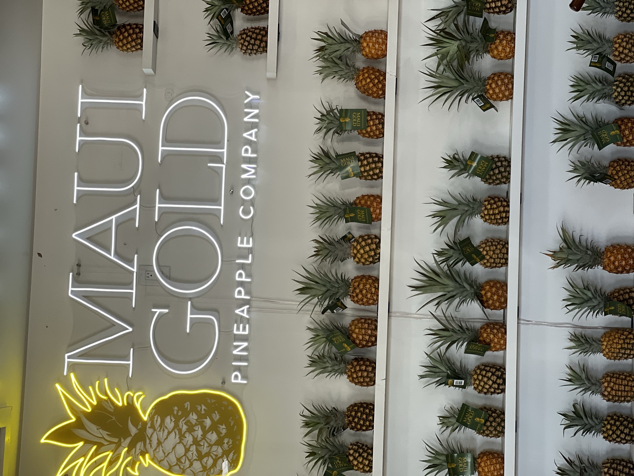Maui Gold Pineapple Company neon sign with pineapple wall display